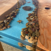 Tabletop with blue resin and pebbles resembling a natural landscape using thickset epoxy