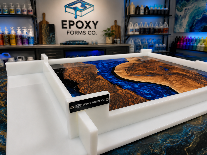 A white Epoxy Forms Co. mold tray containing a polished wood and resin river-edge artwork, photographed in a branded epoxy workshop with shelves of bottles and supplies in the background.